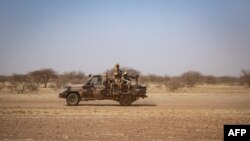 In this file photo taken on Feb. 03, 2020, Burkina Faso soldiers patrol aboard a pick-up truck on the road from Dori to the Goudebo refugee camp.