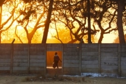 FILE - A woman walks home at sunset in Harare, Zimbabwe, Aug. 7, 2019.
