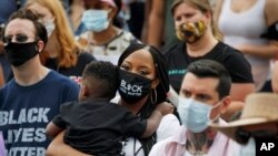 រូបឯកសារ៖ ស្ត្រីម្នាក់ពរ​កូនតូច ខណៈដែលមនុស្សម្នា​ជួបជុំគ្នា​ដើម្បី​​ប្រារព្ធទិវា១៩ មិថុនា ឬ Juneteenth ដែល​ជា​កាល​បរិច្ឆេទ​នៃ​ការ​រួច​ផុត​ពី​ការយក​ជន​ជាតិ​អាមេរិកាំង​ស្បែក​ខ្មៅ​ធ្វើ​ជា​ទាសករ នៅ​សហរដ្ឋ​អាមេរិក នៅ​រដ្ឋធានី​វ៉ាស៊ីនតោន កាលពី​ថ្ងៃសុក្រទី ១៩ ខែមិថុនាឆ្នាំ ២០២០។