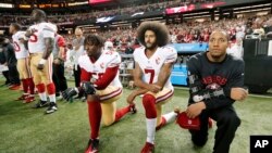 FILE - San Francisco 49ers quarterback Colin Kaepernick (7) and outside linebacker Eli Harold (58) kneel during the playing of the national anthem before an NFL football game against the Atlanta Falcons in Atlanta. 