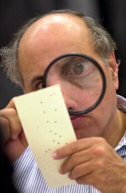 FILE - In this Nov. 24, 2000 photo, a magnifying glass is to examine a disputed ballot at the Broward County Courthouse in Fort Lauderdale, Florida recount.