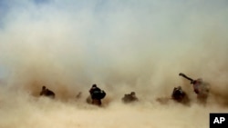 FILE - U.S. soldiers and their Afghan translators shelter from dust kicked up by a Chinook helicopter as it takes off from Mangal Khan village, Khakeran Valley, Zabul province, Afghanistan, June 2005.