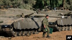 FILE - An Israeli soldier walks past tanks near the Israel and Gaza border, July 10, 2014. 