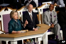 Pennsylvania Gov. Tom Wolf, center, and Pastor James Hall Jr. listen to Democratic presidential candidate Hillary Clinton speak at Triumph Baptist Church in Philadelphia, April 24, 2016.