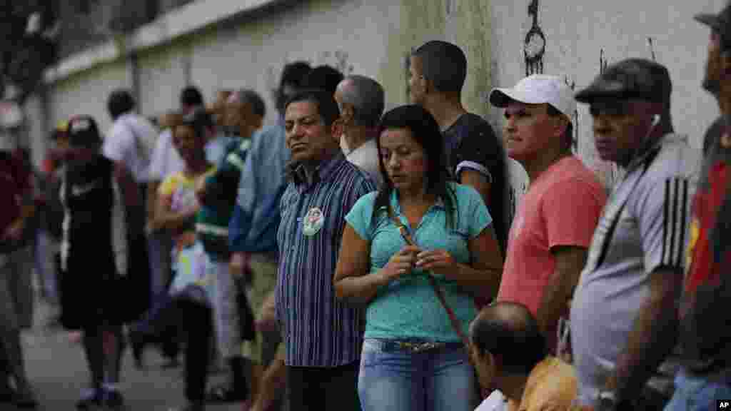 People wait in line to vote in general elections outside a school at the Mare Complex slum in Rio de Janeiro, Brazil, Oct. 26, 2014. 