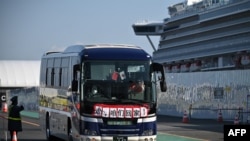 A bus with “Go, we go back to home” on the front transfers passengers from the Diamond Princess in Yokohama, Feb. 21, 2020. Hundreds of people have left the ship after testing negative for the disease and many have returned home and further quarantine.