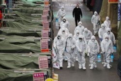 Workers wearing protective gear spray disinfectant at a market in the southeastern city of Daegu, South Korea, as a preventive measure after the COVID-19 coronavirus outbreak.