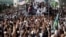 FILE - Supporters of the Tehreek-e-Labbaik Pakistan (TLP) Islamist political party raise their hands as they listen to the speech of their leader during a protest march to condemn a cartoon competition by the Netherlands, in Lahore, Pakistan, Aug. 29, 2018. 