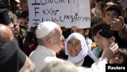 Paus Fransiskus menyalami para migran dan pengungsi di kamp penampungan pengungsi dekat pelabuhan Mytilene, Lesbos, Yunani (16/4). 