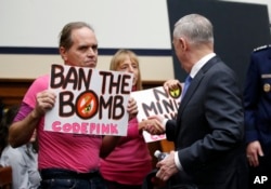 Defense Secretary Jim Mattis, right, shakes hands with Medea Benjamin of Code Pink, a peace and social justice activist group, as he arrives for a hearing of the House Armed Services Committee on Capitol Hill, Feb. 6, 2018, in Washington.