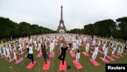 People gather for yoga near the Eiffel tower in Paris, France June 17, 2018. (REUTERS/Philippe Wojazer)