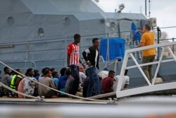 FILE - A police officer speaks to rescued migrants after they arrived on an Armed Forces of Malta patrol boat in Valletta's Marsamxett Harbor, Malta, Sept. 21, 2019.