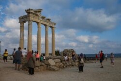 Tourists visit the 150A.D Roman temple dedicated to Apollo the Greek and Roman god of music, harmony and light, in Antalya, southern Turkey, June 20, 2021