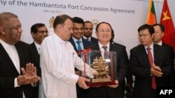 Sri Lanka's Minister of Ports & Shipping Mahinda Samarasinghe (C) exchanges souvenirs with Executive Vice President of China Merchants Port Holdings Dr. Hu Jianhua (3-R) during the Hambantota International Port Concession Agreement at a signing ceremony in Colombo, Sri Lanka, July 29, 2017. 
