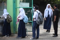 Petugas keamanan memeriksa suhu tubuh para siswa sebelum mereka memasuki halaman sekolah mereka di Bekasi, pinggiran Jakarta, 13 Juli 2020.