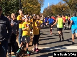 FILE - Teens wearing cow-horn hats and ringing cow bells cheer on runners in the Marine Corps Marathon along Independence Avenue in Washington in October 2014.