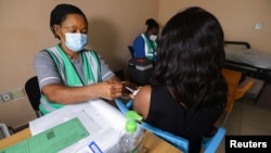 A medical worker injects the AstraZeneca's coronavirus disease (COVID-19) vaccine to a woman at the Nationa Hospital in Abuja, Nigeria March 31, 2021.