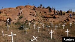 FILE - Members of South Africa's mining community walk near crosses placed at a hill where 43 miners died during clashes with police in 2012 at Lonmin's Marikana platinum mine in Rustenburg, northwest of Johannesburg, May 14, 2013.