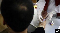 A man has a sample of blood taken by a nurse for testing at the HIV/AIDS ward of Beijing YouAn Hospital. The number of new HIV/AIDS cases in China is soaring, with rates of infections among college students and older men rising. 