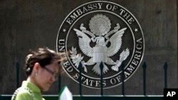 FILE - A woman checks her documents as she walks past the U.S. Embassy in Beijing, China, May 6, 2011.