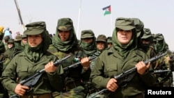 FILE - Sahrawi women soldiers carry their weapons during a parade at the Awserd refugee camp in Tindouf, Algeria, Feb. 27, 2021.
