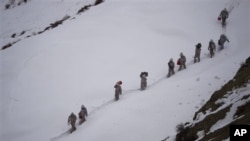 Tentara Pakistan membawa perbekalan menuju Kalpani Base, pos militer Pakistan di Kashmir utara. Pos ini terkubur salju longsor, Sabtu (7/4).