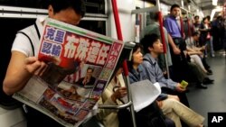 Một hành khách trên một chuyến xe điện ngầm ở Hong Kong đọc nhật báo có đăng các bài về bầu cử tổng thống ở Mỹ