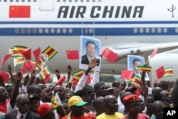 FILE - Zimbabweans wave flags while welcoming Chinese President Xi Jinping in Harare, Zimbabwe, Dec. 1, 2015. Xi visited Zimbabwe for a two-day State visit aimed at strengthening relationships between the two countries.