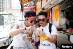 From left, Cheng Lai, 30, Jennifer Wu, 26, and Adam Lo, 28, take part in the world's first "Pokemon Go competition in Hong Kong, China, Aug. 6, 2016.