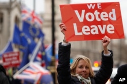 FILE - A pro-Brexit demonstrator waves a placard with others outside the Houses of Parliament in London, Britain, Dec. 18, 2018.