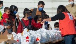 A member of the Red Cross provides essential resources to Afghan evacuees at Ramstein Air Base, Germany, Aug. 21, 2021. (Airman Edgar Grimaldo/U.S. Air Force photo)