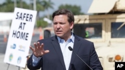 FILE - Florida Governor Ron DeSantis speaks during a news conference at a drive-through coronavirus testing site in front of Hard Rock Stadium, in Miami Gardens, Florida, March 30, 2020.