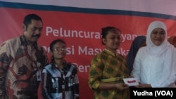 Menteri Sosial Khofifah Indar Parawansa (kanan) didampingi walikota Solo, F.X. Hadi Rudyatmo (kiri) membagikan kartu elektronik e-warong bagi warga miskin di Solo. (Foto: Dok)