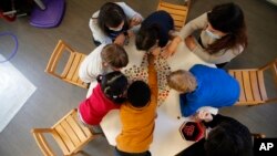 FILE- Children play with a therapist in the pediatric unit of the Robert Debre hospital, in Paris, France, March 2, 2021. 