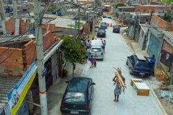 After going to a little forest close to his home, Juarez Viana returns with the wood he will use to cook for a week, in Sao Paulo, Nov. 14, 2021. (Yan Boechat/VOA)
