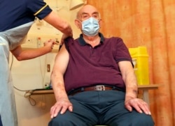 82-year-old Brian Pinker receives the Oxford University-AstraZeneca COVID-19 vaccine from nurse Sam Foster at the Churchill Hospital in Oxford, southwest England on January 4, 2021.