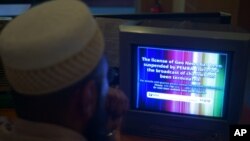 FILE - A Pakistani viewer looks at a television screen flashing suspension notice of GEO News channel in Islamabad, Pakistan.