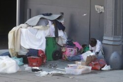 FILE - A homeless person sits on a sidewalk amid the coronavirus pandemic, in San Francisco, California, April 2, 2020.