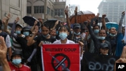 Anti-coup protesters flash the three-finger salute and chant slogans in Yangon, Myanmar, during a rainy April 30, 2021, demonstration against the military coup.