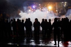 FILE - Riot police fire tear gas at supporters of the Shi'ite Hezbollah and Amal groups in Beirut, Dec. 17, 2019.