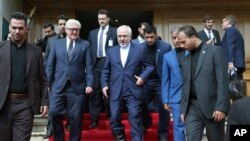 Iranian Foreign Minister Mohammad Javad Zarif, center, and his German counterpart Frank-Walter Steinmeier, center left, leave the Munich Security Conference venue in Tehran, Iran, Saturday, Oct. 17, 2015. 