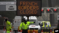 A police officer redirects traffic at the entrance to the closed ferry terminal in Dover, England, Dec. 21, 2020, after the Port of Dover was closed and access to the Eurotunnel terminal suspended.