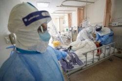 FILE - Medical workers in protective suits attend to a patient inside an isolated ward of Wuhan Red Cross Hospital in Wuhan, the epicenter of the novel coronavirus outbreak, in Hubei province, China February 16, 2020.