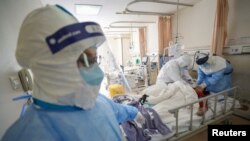 Medical workers in protective suits attend to a patient inside an isolated ward of Wuhan Red Cross Hospital in Wuhan, Hubei province, China, Feb. 16, 2020. 