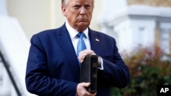 FILE - President Donald Trump holds a Bible as he visits outside St. John's Church across Lafayette Park from the White House, June 1, 2020.