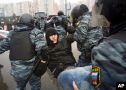 FILE - Policeman detain a protester during a march to mark National Unity Day, in Moscow, Russia, Nov. 4, 2013. Several thousand Russian nationalists rallied against the migrants they accuse of pushing up the crime rate and taking their jobs.