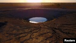 A truck stirs up dust on a road behind a dam on farmer May McKeown's drought-affected property located on the outskirts of the northwestern New South Wales town of Walgett in Australia.