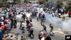 Warga Palestina menghindari gas air mata yang ditembakkan oleh polisi Israel di kota tua Yerusalem (21/7). 