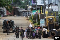 Philippine troops escort civilians, as a military truck covers them from sniper fire, in a village on the outskirts of Marawi on the southern island of Mindanao, May 31, 2017, as fighting between government forces and Islamist militants continues.