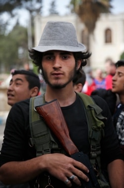 FILE - A Turkey-backed opposition fighter of the Free Syrian Army stands at a food distribution center, in the northwestern city of Afrin, Syria, during a Turkish government-organized media tour into northern Syria, March 24, 2018.